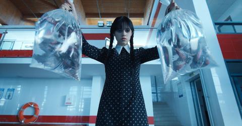 Wednesday Addams (Jenna Ortega) holding two bags of fish in 'Wednesday'