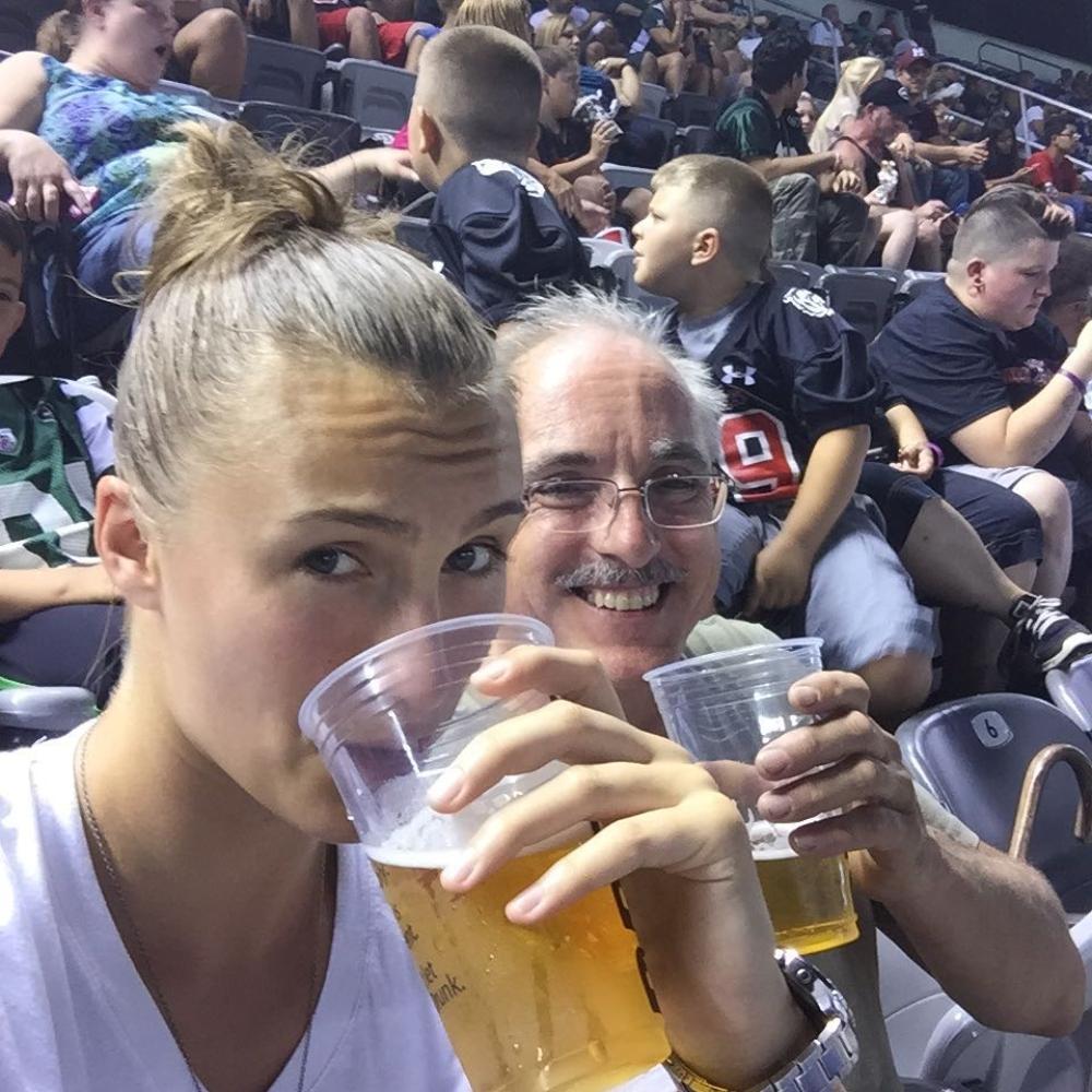 Kristin Lietheuser sits at a game and drinks a beer with her dad, Donald Leitheuser. 