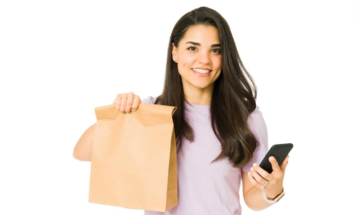 A woman holding a bag with takeout and a food