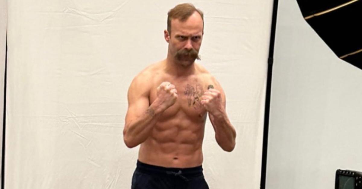 A shirtless Nathan Barnatt poses for photos with raised fists