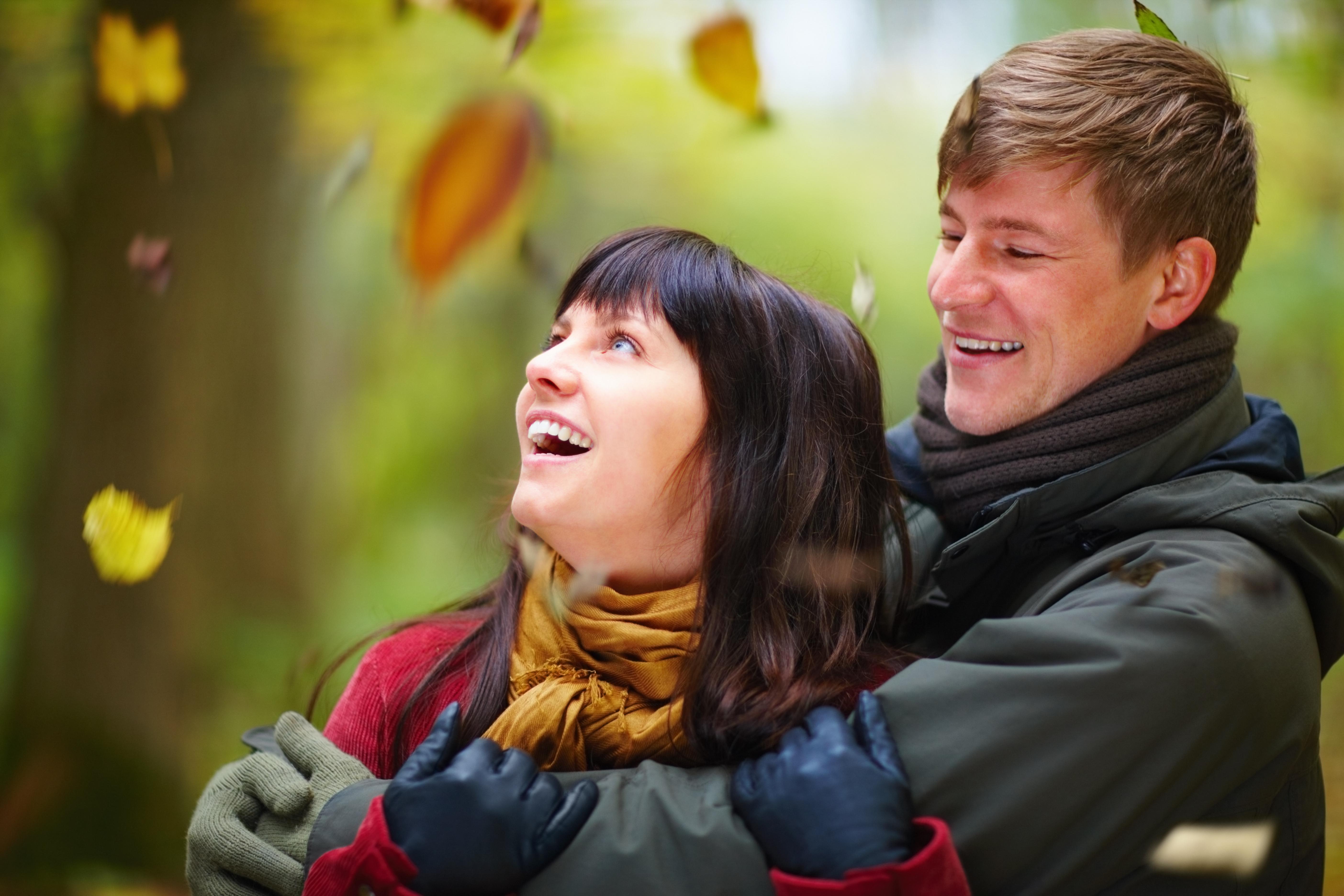 A couple with leaves falling down around them.