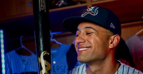 J.C. Escarra looking at a bat in a locker room.