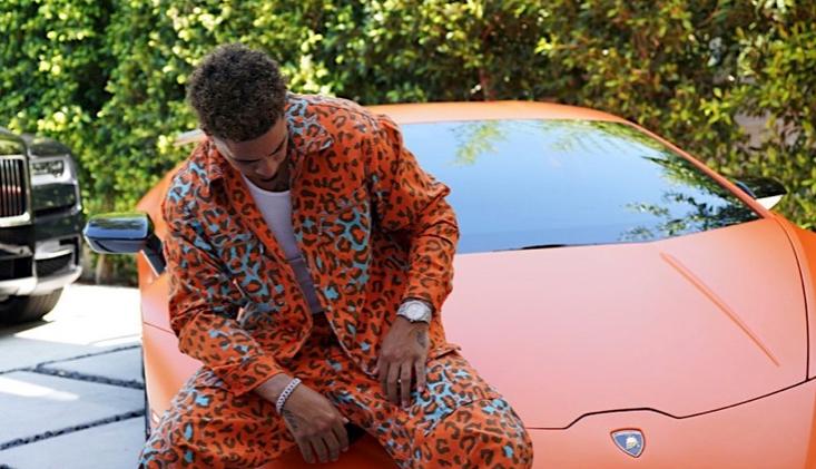 Austin McBroom posting in an orange cheetah-print suit in front of a lambo