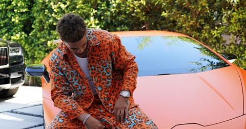 Austin McBroom posting in an orange cheetah-print suit in front of a lambo