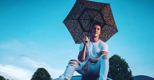 Sam taking a photo on top of one of his cars.