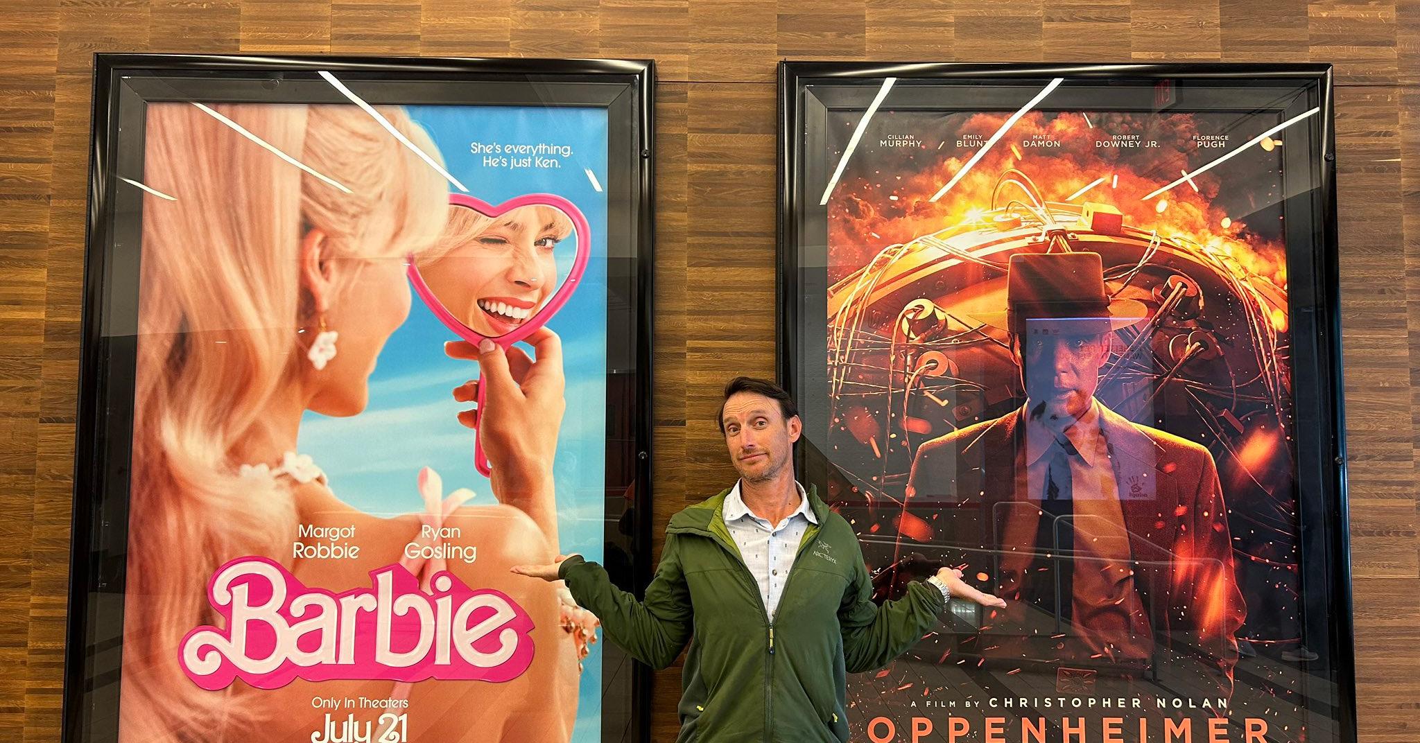 Charles Oppenheimer standing in front of 'Barbie' and 'Oppenheimer' posters. 