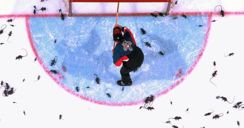 Aerial view of arena custodian cleaning plastic rats thrown by fans onto ice after Florida Panthers goal.