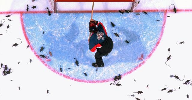 Aerial view of arena custodian cleaning plastic rats thrown by fans onto ice after Florida Panthers goal.