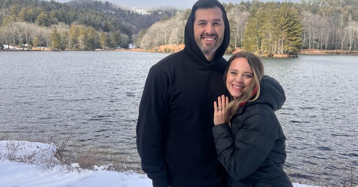 Jeremy Vuolo and Jinger Duggar stand together in front of a lake with snow