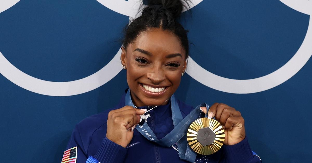 Gold medalist Simone Biles of Team United States poses with the Olympic Rings and a goat charm on her necklace during the Artistic Gymnastics Women's All-Around Final medal ceremony on day six of the Olympic Games Paris 2024 at Bercy Arena on August 01, 2024 in Paris, France. (Photo by Jamie Squire/Getty Images)