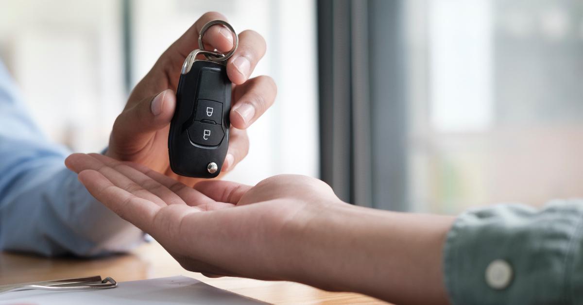 Car salesman hands over the keys to a new car owner.