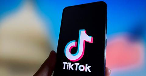A TikTok logo on a phone screen being held by a person.