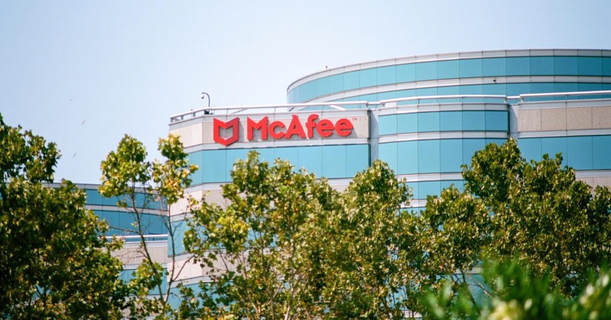 A McAfee logo on the side of a building with trees in front. 