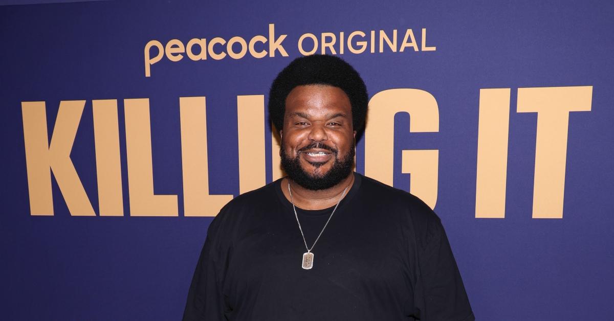 Craig Robinson wears a black shirt and chain, smiles at the 2022 red carpet premiere of 'Killing It'. 