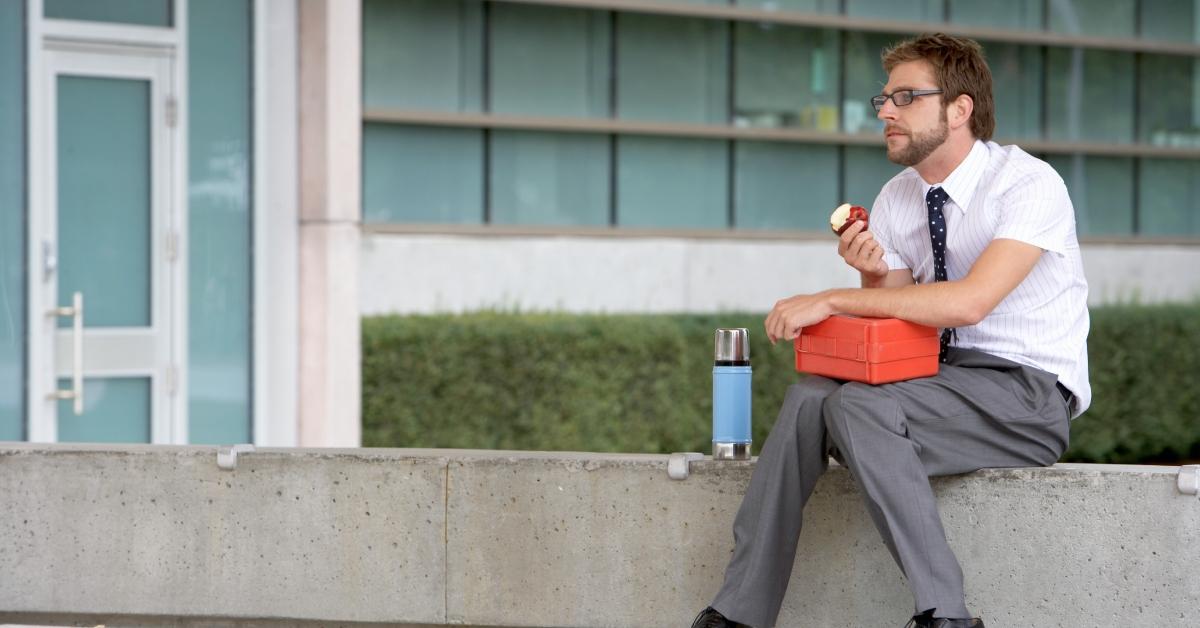 Businessman with lunch bag, eating outside alone