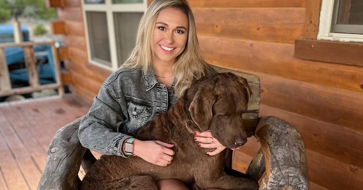 Kylie Blakely holds a chocolate Labrador in her lap 