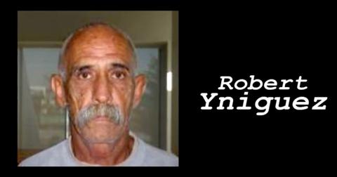 Robert Yniguez stands in front of a window, not smiling