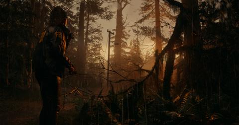 'Alan Wake 2' Saga Anderson standing in a rainy forest at sunset.
