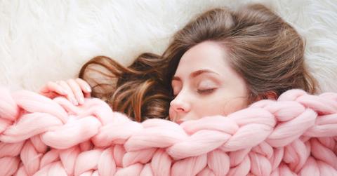 young woman with long brown hair sleeping under warm knitted peach picture id