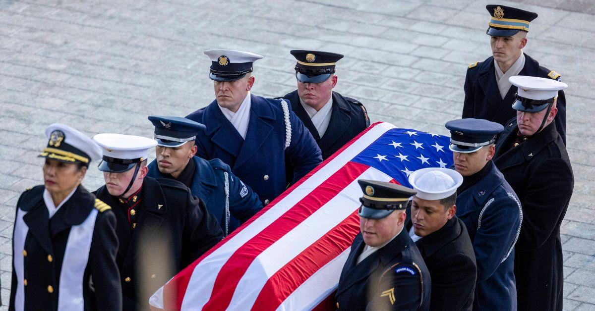 Jimmy Carter's casket being carried with an American flag over it. 