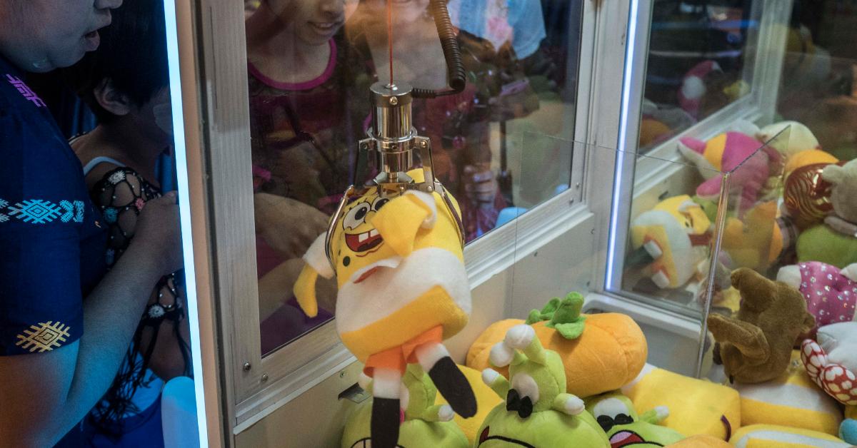 Kids play a claw game at an arcade.