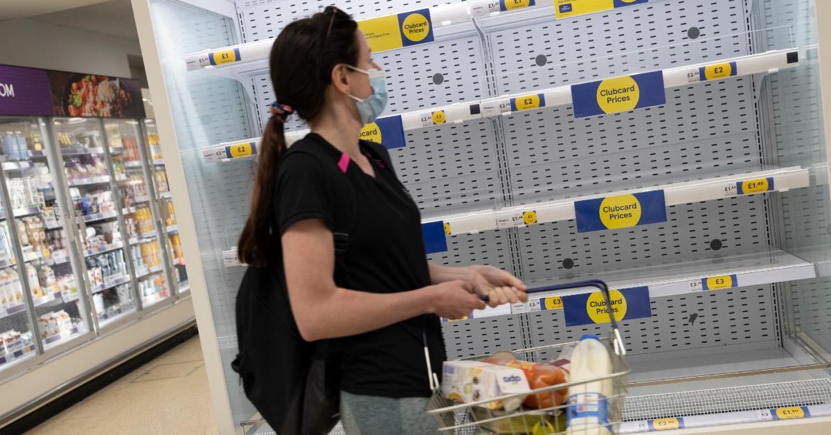 woman passing by empty shelves at grocery store