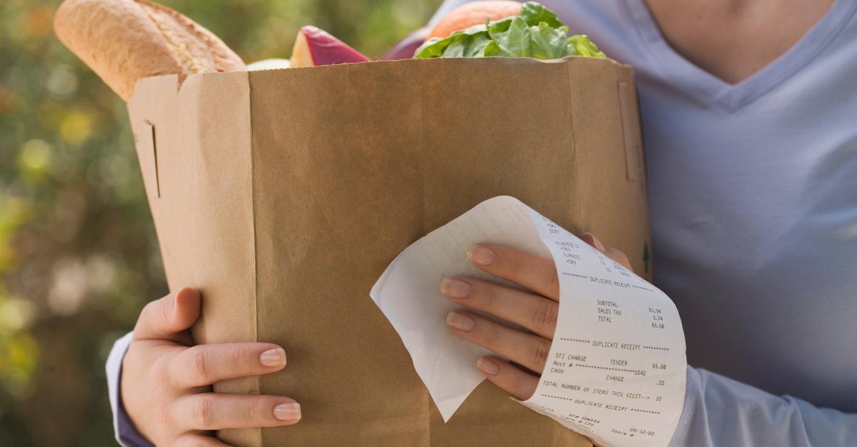 Woman holding grocery bag and receipt - stock photo