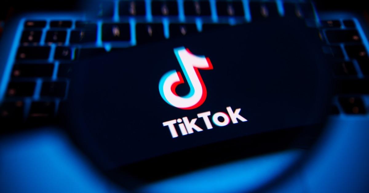 A TikTok logo on a phone sitting on a laptop keyboard. 