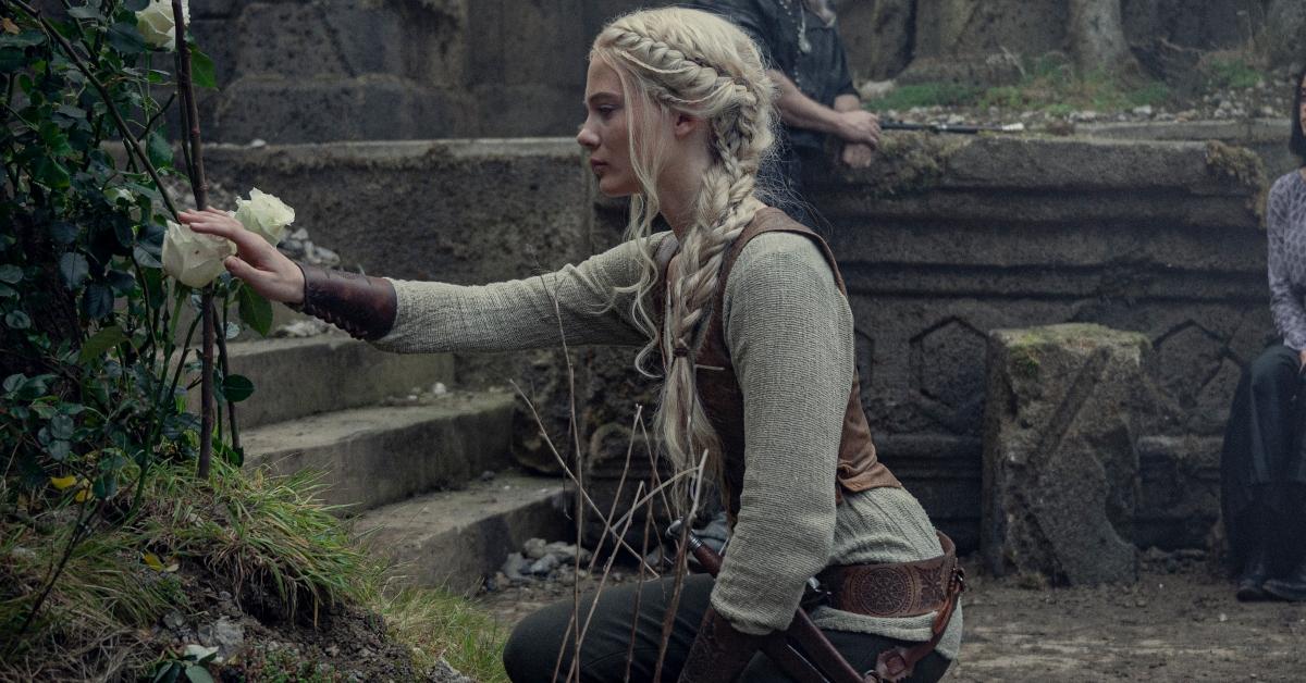 Ciri kneeling and touching a rose in 'The Witcher'