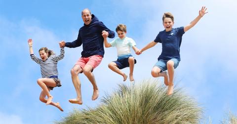 A photo of Prince William and his kids jumping over a sand dune.