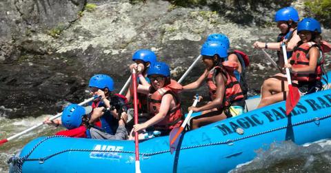 'Bug Juice' campers in a blue raft as they navigate a river