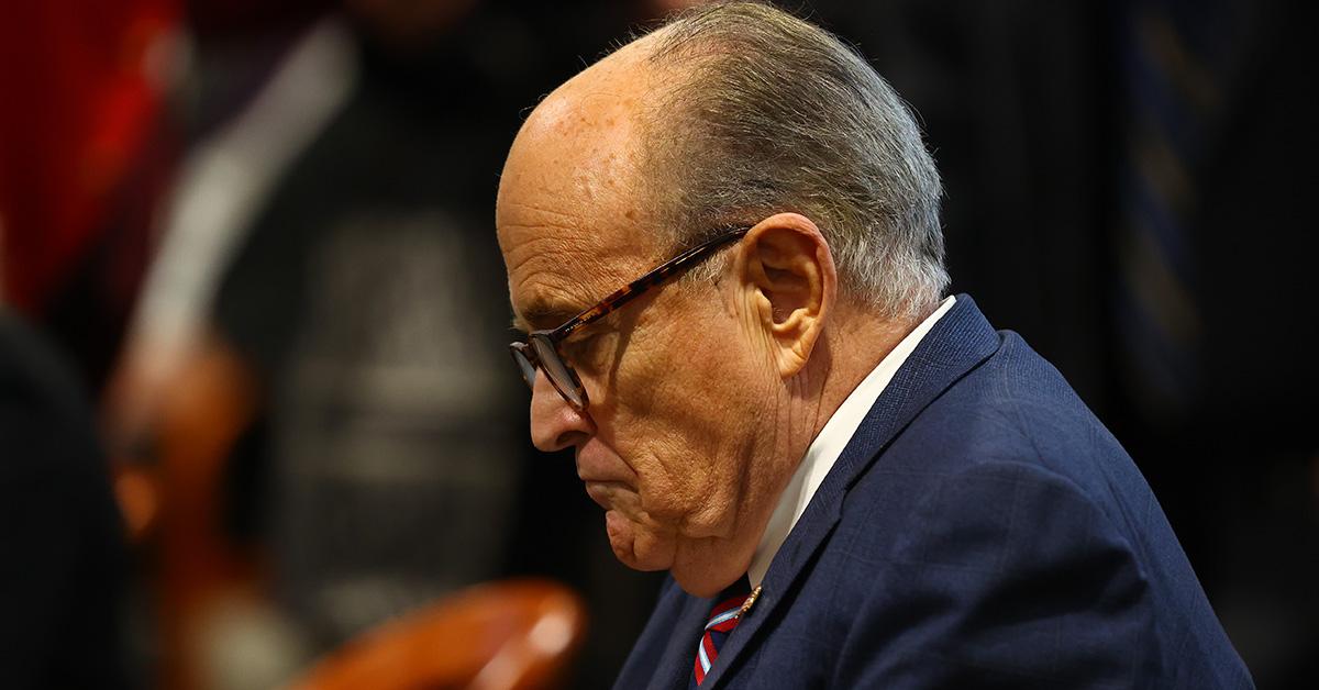 Rudy Giuliani looking down with glasses on. 