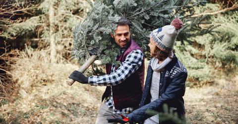 man and woman walking with freshly cut down christmas tree
