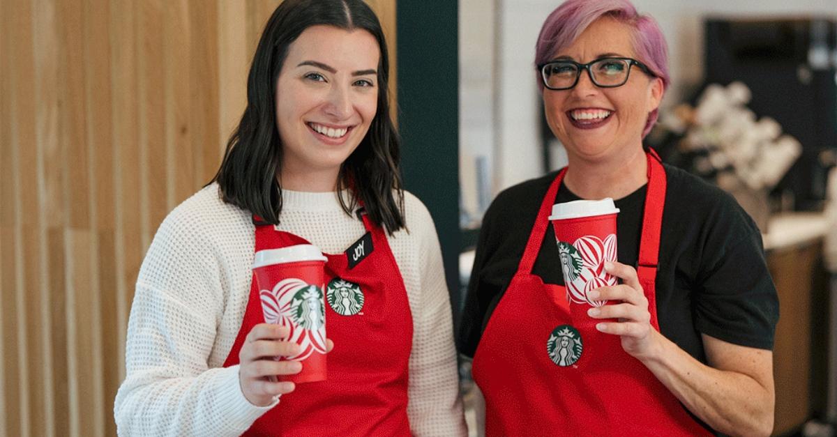 Two Starbucks employees holding the free reusable red cup.