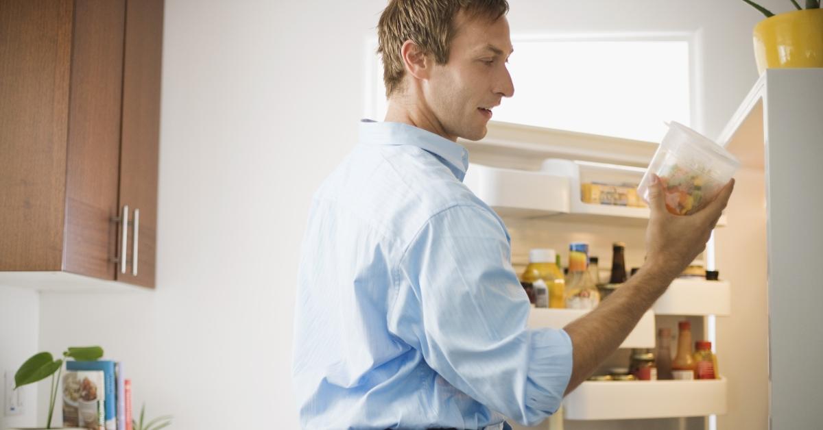 Man with leftovers at an open refrigerator
