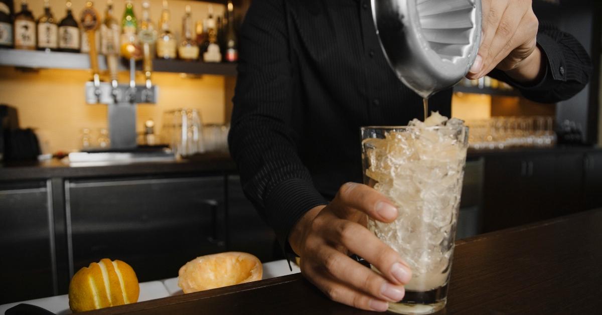 Bartender pouring juice into cocktail shaker - stock photo