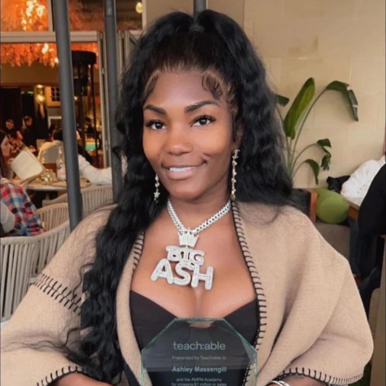 Social media star and accused scammer Ashley Grayson poses with a crystal plaque and wears large diamond chain.