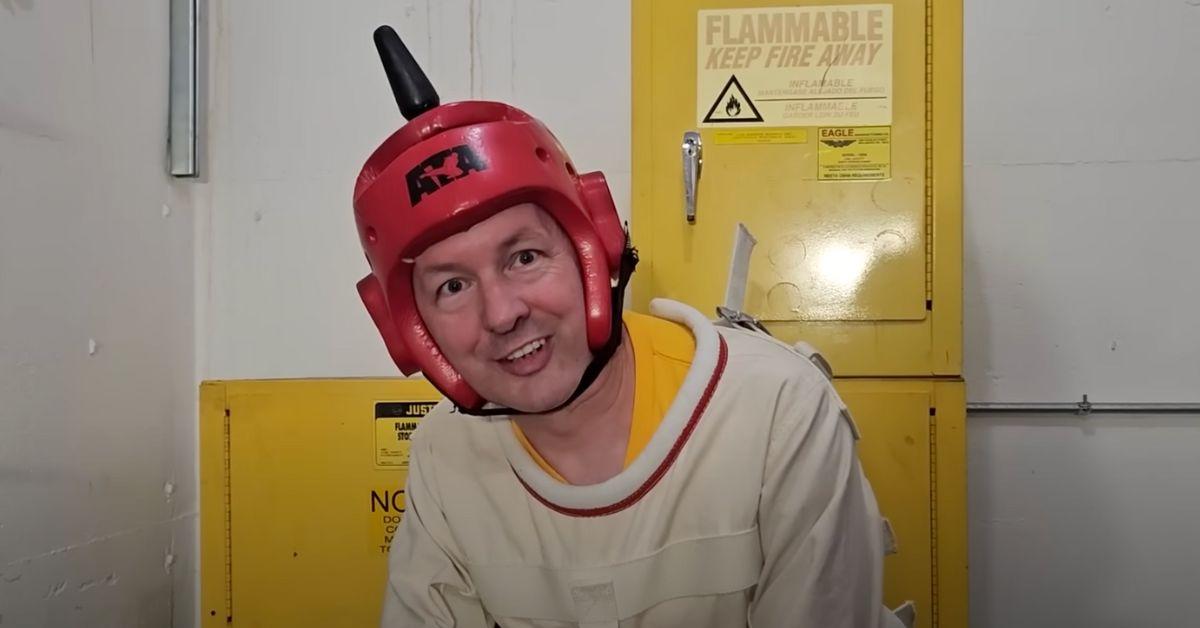 Chris Boden in a straightjacket with a helmet on. 