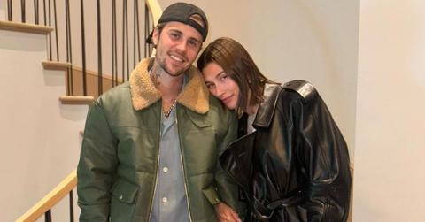 Justin and Hailey Bieber wear coats and cuddle on a staircase