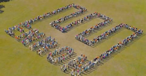 A group of people making the Enron logo.