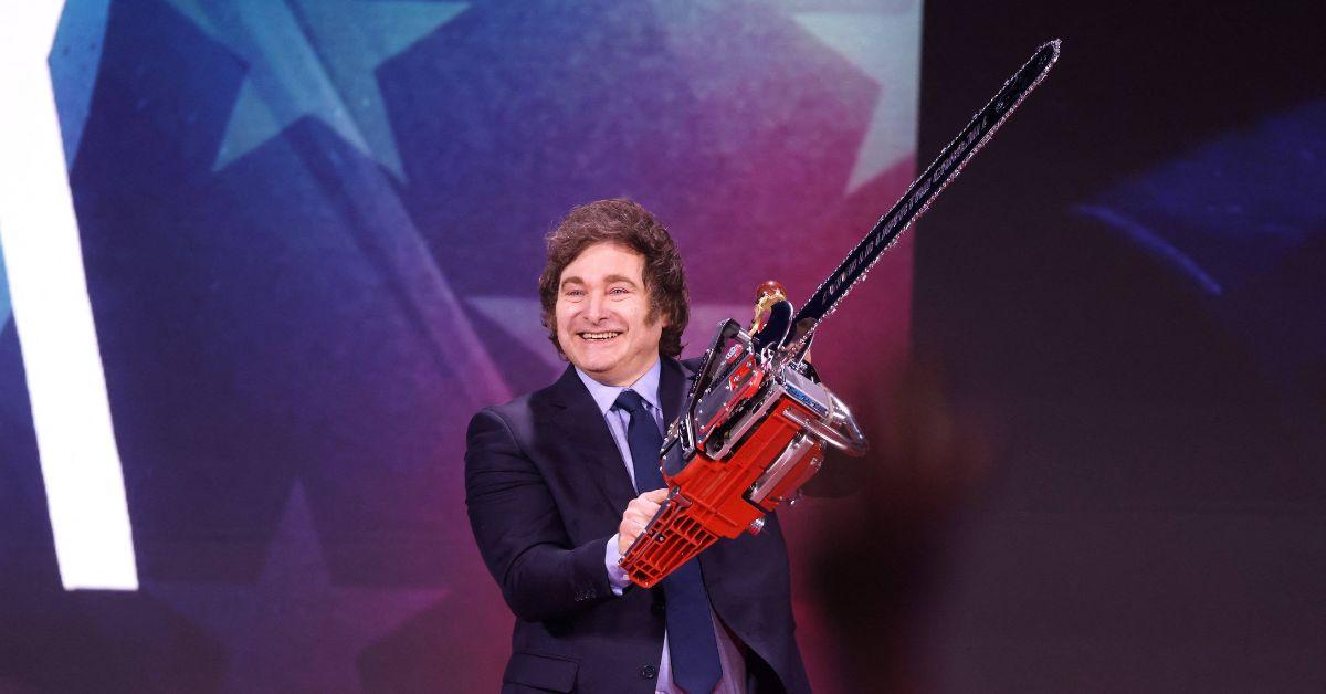 Javier Milei holding a chainsaw on stage. 