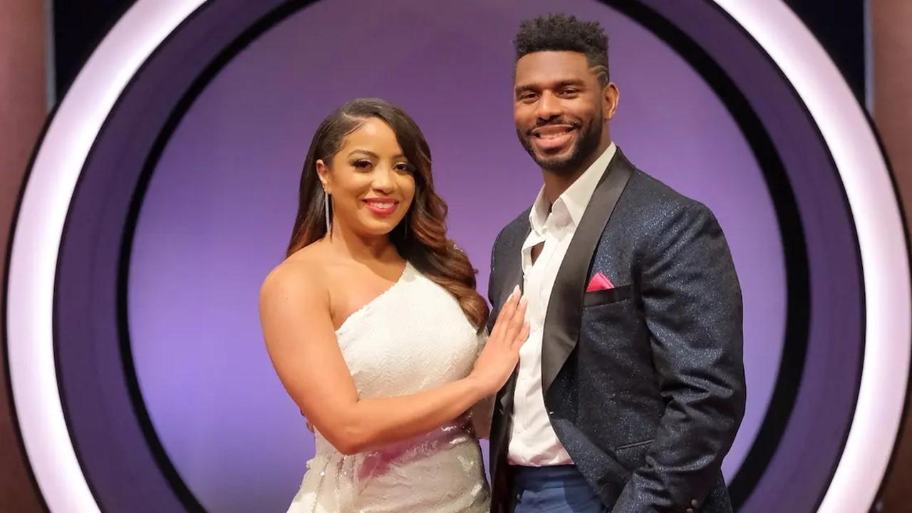 Tiffany and Brett Brown standing in front of a purple circular backdrop in formal attire.