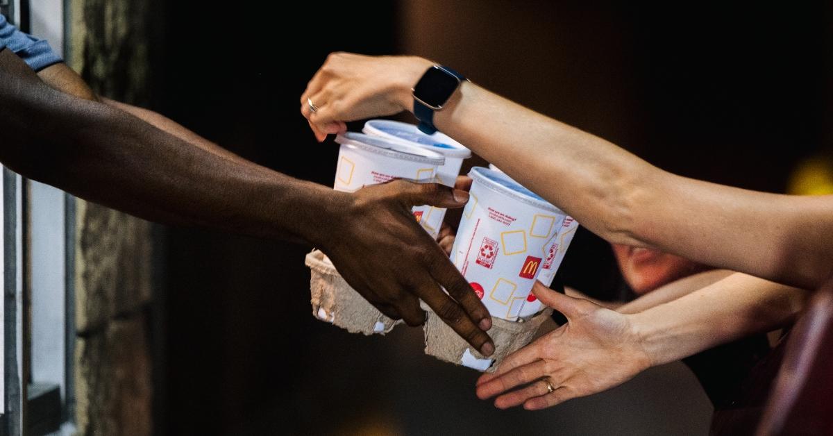 : A McDonald's employee hands a customer her food in a McDonald's drive-thru.