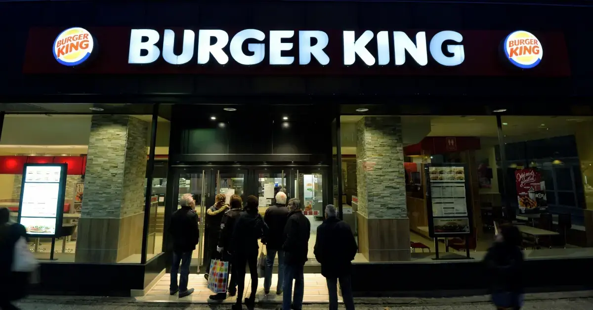 A group of people standing outside of a Burger King restaurant 