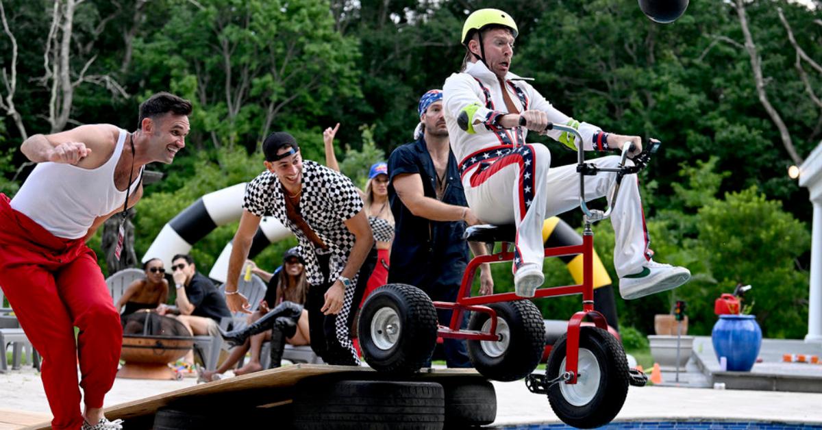 (L-R) Kyle Cooke rides a tricycle into a pool as Carl Radke, Jesse Solomon, and Craig Conover smile and watch in Season 8 of 'Summer House.'