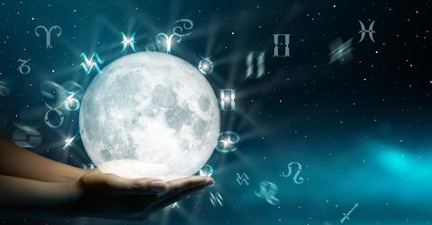 A person holding the globe with zodiac signs around it