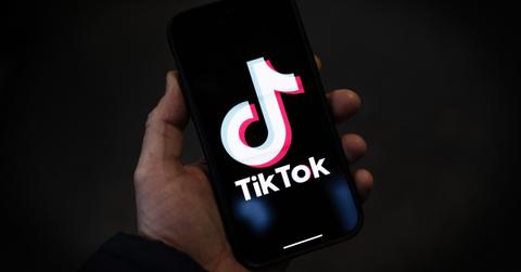A person holding a phone looking at the TikTok app.