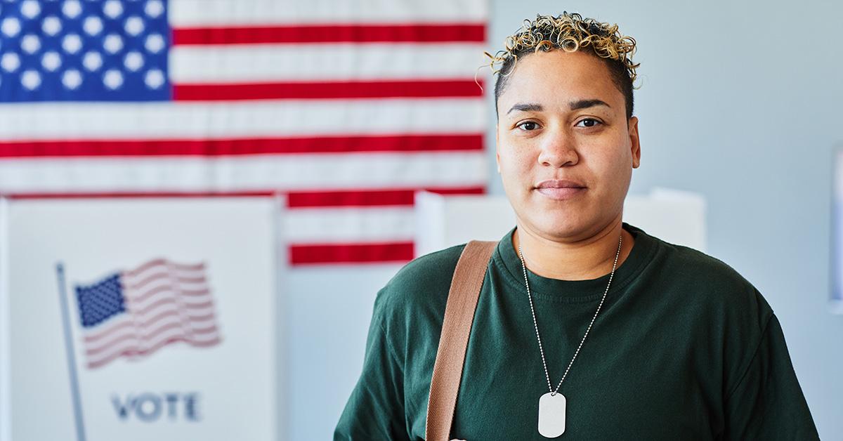 A person standing in front of a voting booth. 