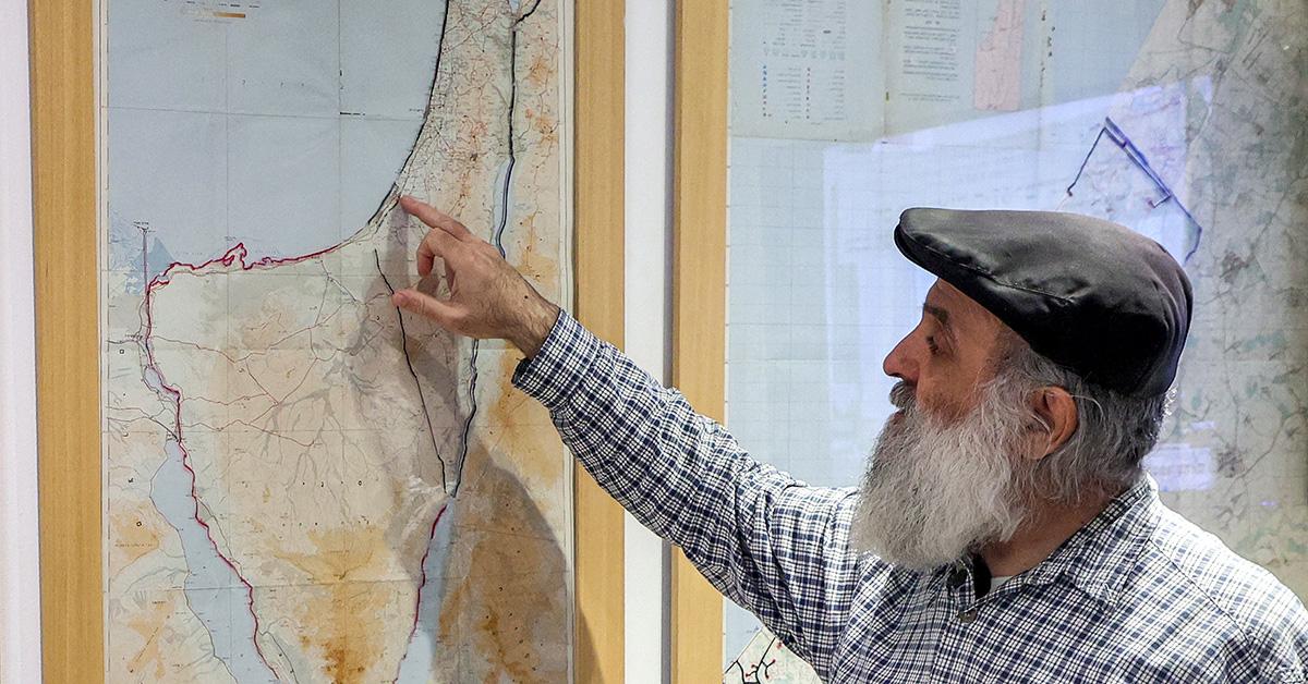 A man pointing at a map of Israel and Palestine. 