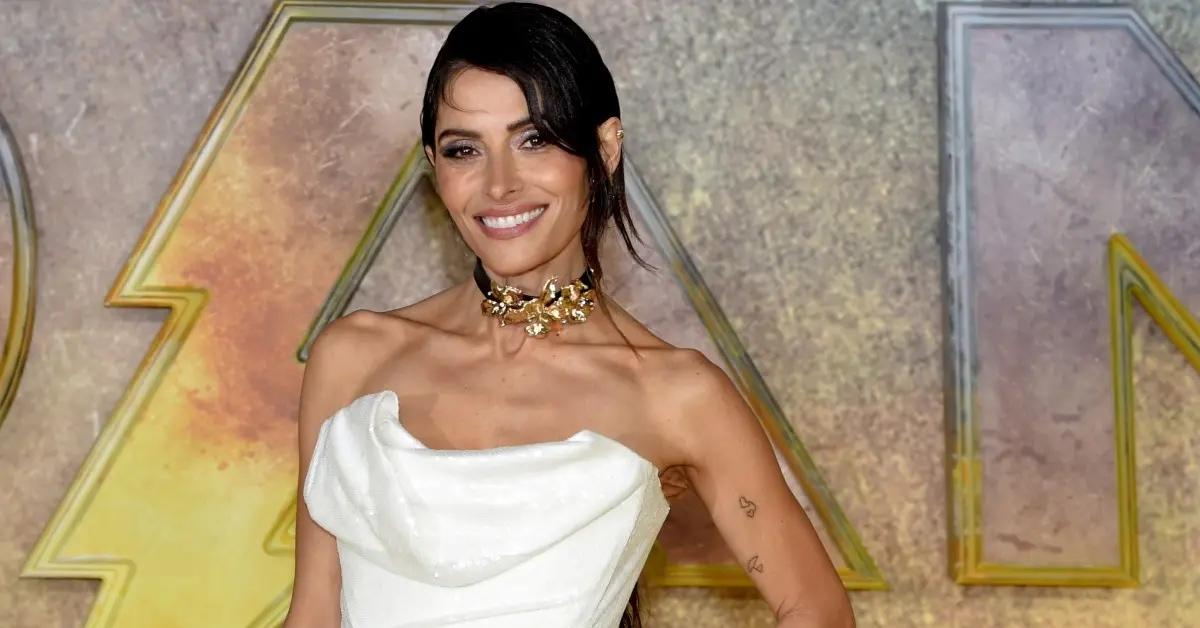 Sarah Shahi wearing a white dress to a red carpet event.